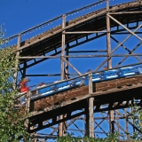 The blue car speeds by at the roller coaster