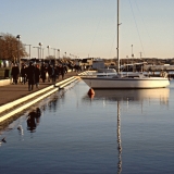 A sail boat and people on a walk