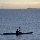 A paddler passes Uunisaari island, Harmaja light house in the background