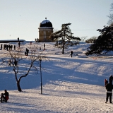 People sliding down the hill in a wintery Kaivopuisto park