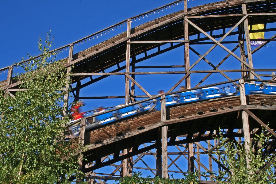 The blue car speeds by at the roller coaster