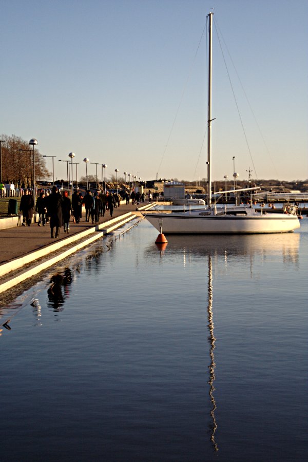 A sail boat and people on a walk