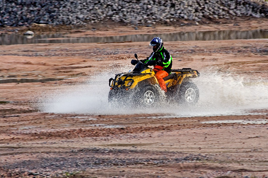 An all terrain vehicle driving through a puddle of water