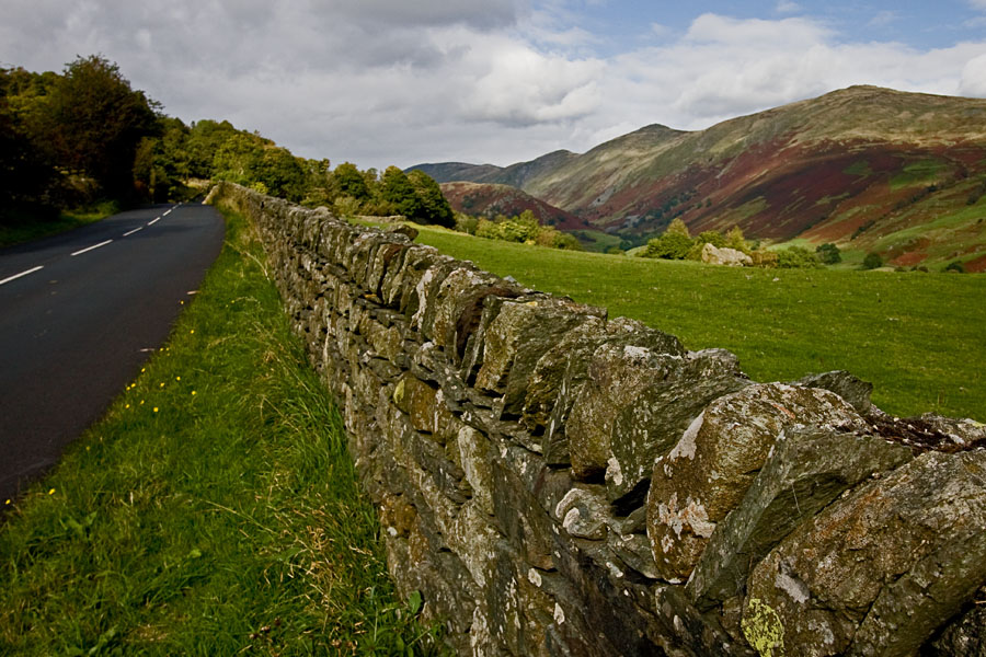 A road, a stone wall and a valley